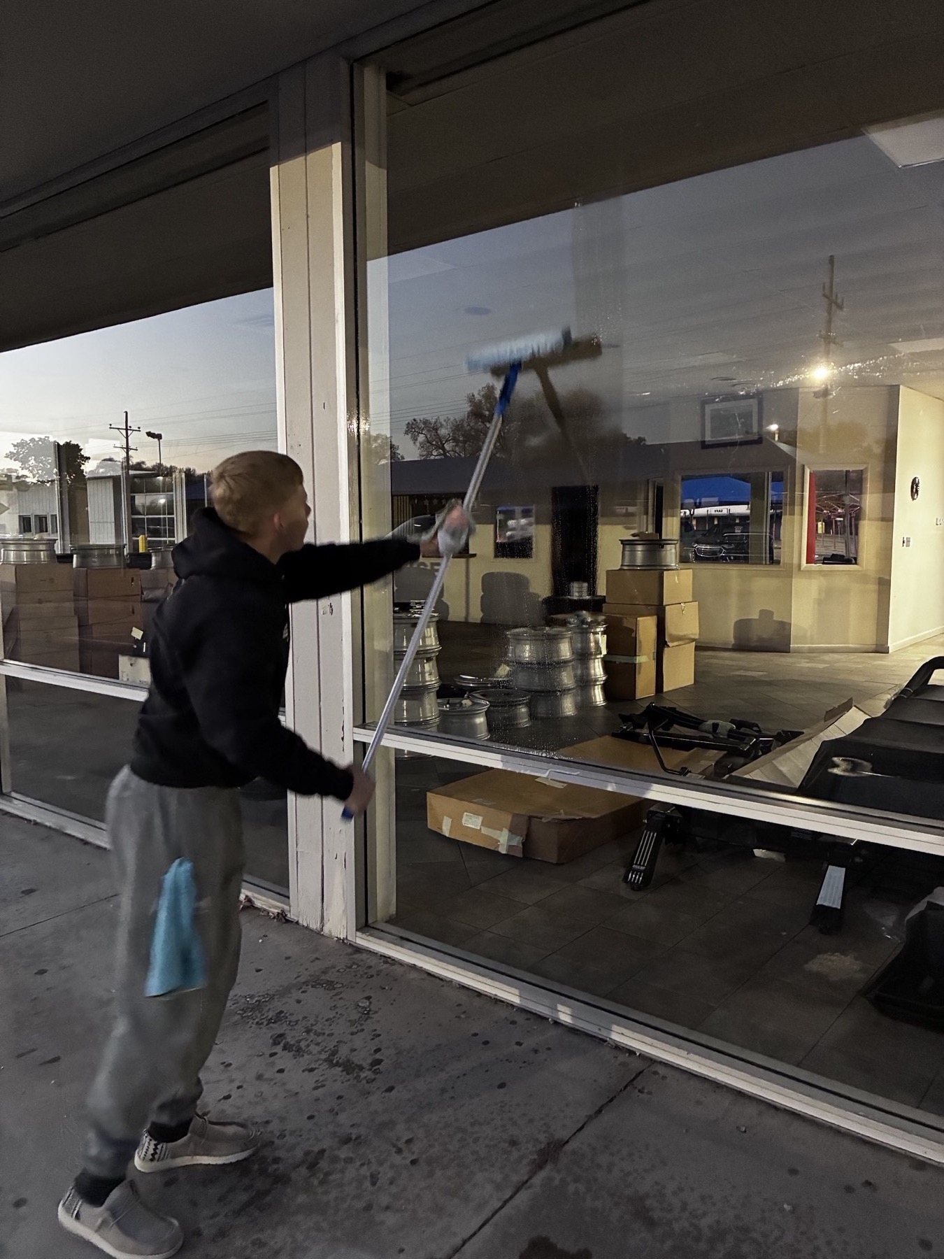 Cleaning a downtown storefront window at dusk