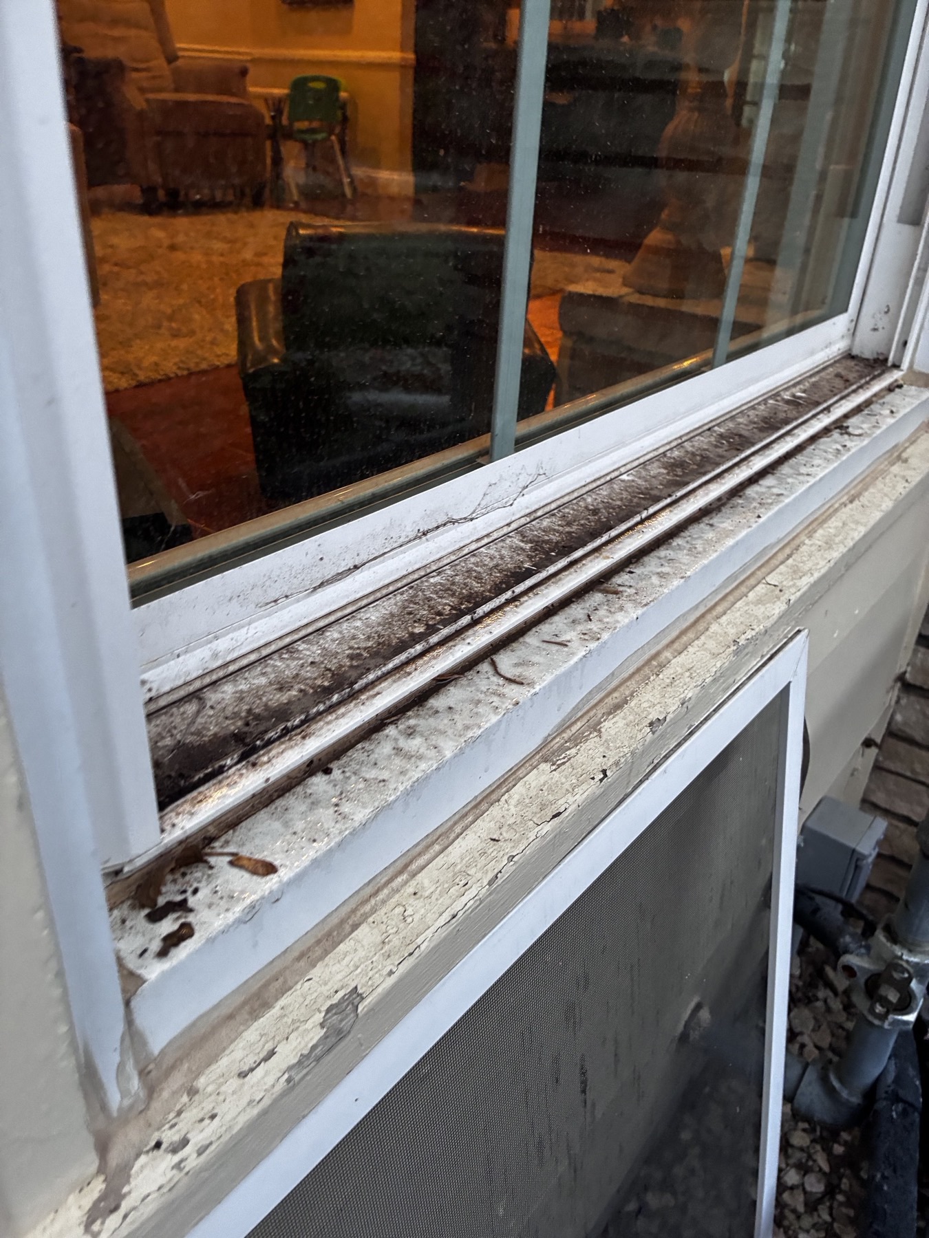 Window sill and track packed with dirt and debris before cleaning