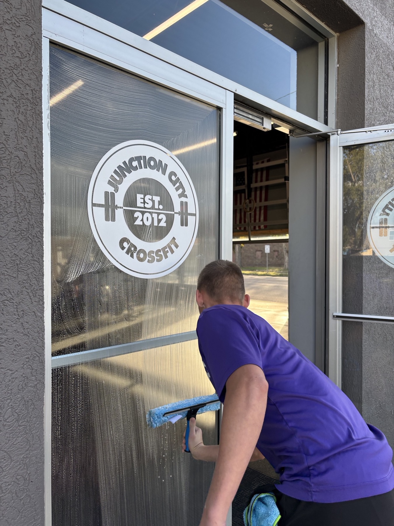 Technician squeegeeing the front door glass at Junction City CrossFit