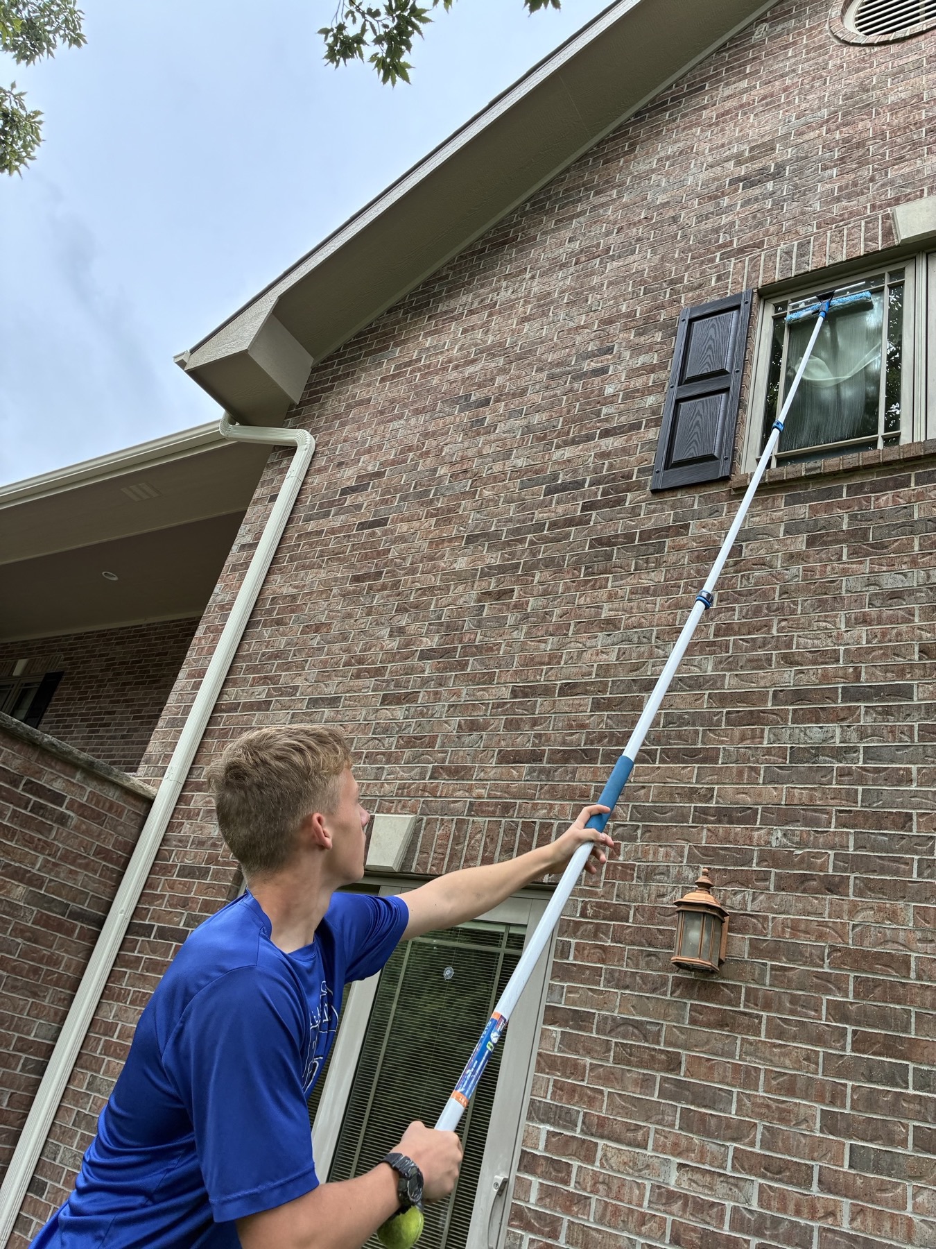 Eagle Exteriors technician reaching a high window with an extension pole