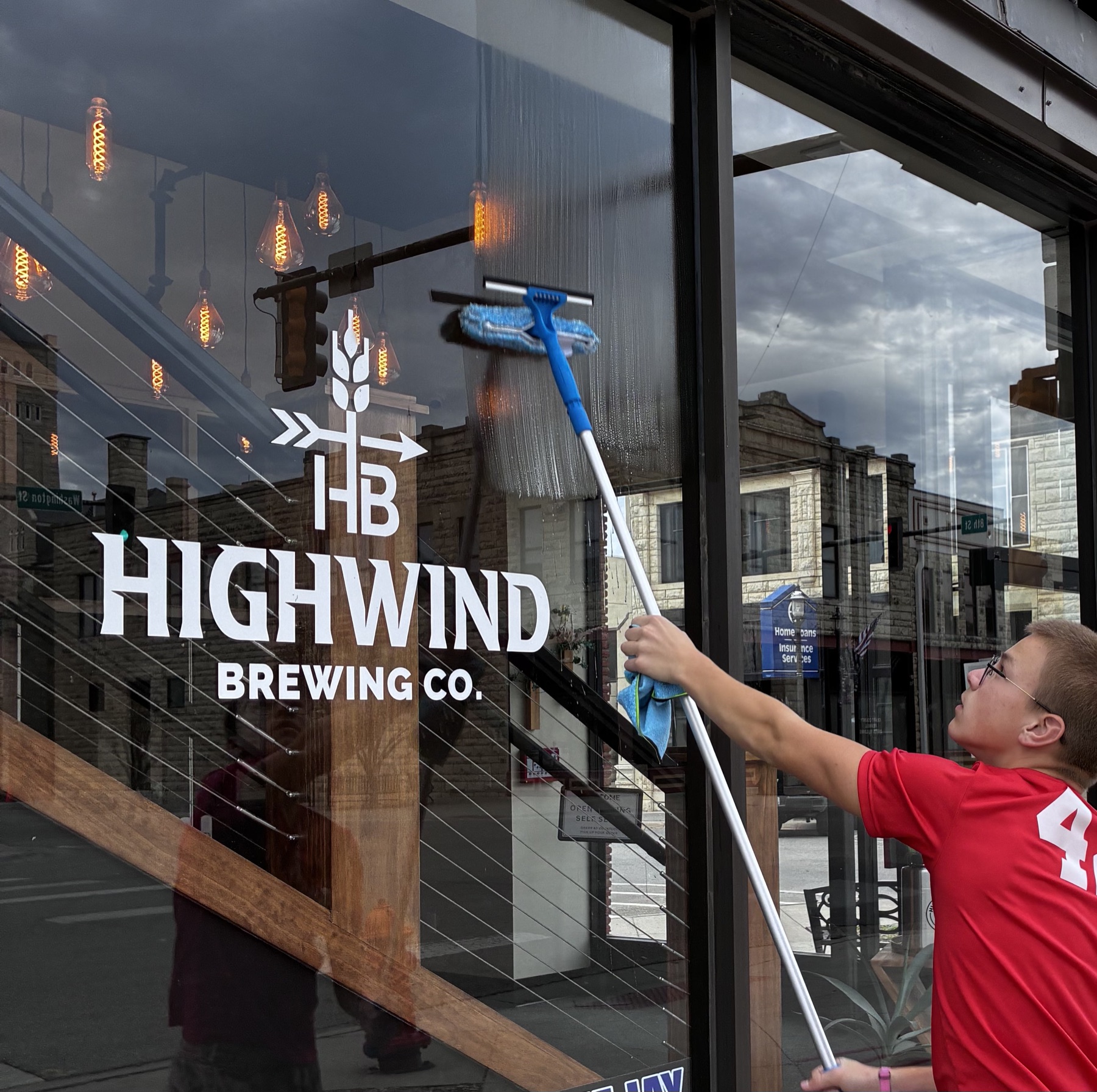 An Eagle Exteriors technician squeegeeing a downtown storefront window in Junction City